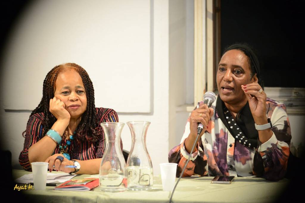 A close-up of two participants at the Panel. One is listening intently while the other is holding the microphone and talking.