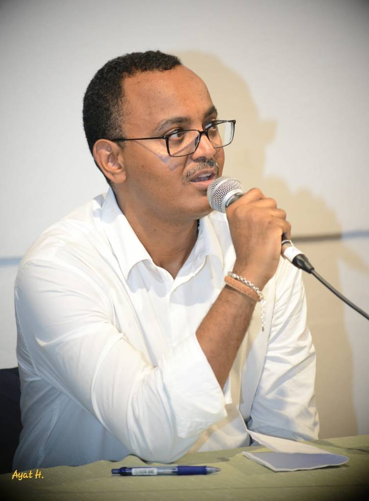 A picture of another man, holding the microphone and speaking